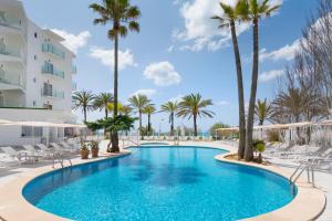 una piscina en un complejo con palmeras y sillas en HSM Golden Playa en Playa de Palma