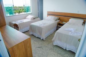 Cette chambre comprend 2 lits et une table. dans l'établissement Pousada Barreirinhas, à Barreirinhas