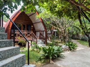 a house with a curved roof and stairs in a garden at Gili Turtle Beach Resort in Gili Trawangan