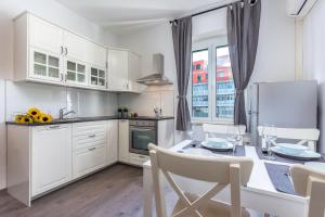 a kitchen with white cabinets and a table with chairs at Stay IN apartment in Rijeka