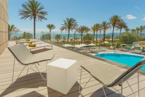 a balcony with chairs and a pool and palm trees at HM Tropical in Playa de Palma