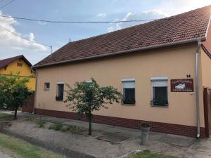 un edificio con ventanas y un árbol delante de él en Szundivendégház en Mórahalom