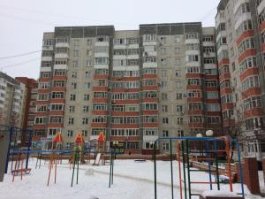 a large apartment building with a playground in the snow at Апартаменты на Пермякова in Tyumen