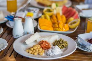 a wooden table topped with plates of food and fruit at Ceyloni Lake Residency in Kandy