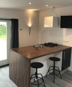 a kitchen with a wooden island with two bar stools at Beach lodge in Zandvoort