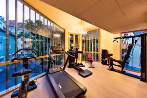 un gimnasio con cintas de correr y elípticas en una habitación con ventanas en Parkhotel Graz - Traditional Luxury en Graz