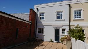 a white house with a brick wall and a patio at Island View in Lymington