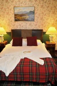 Schlafzimmer mit einem Bett mit weißer Bettwäsche und roten Kissen in der Unterkunft Loch Ness Lodge Hotel in Drumnadrochit