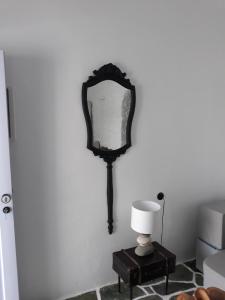 a mirror on a wall next to a table with a lamp at AMO Folegandros in Karavostasi