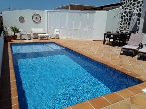una piscina de agua azul en una habitación con sillas y mesa en Las Arecas Villa, en Yaiza