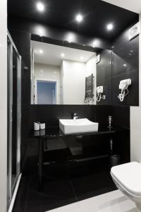 a black bathroom with a sink and a mirror at Kazimierz Residence in Krakow