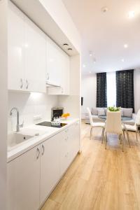 a kitchen with white cabinets and a living room at Kazimierz Residence in Krakow