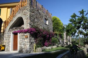 un bâtiment en pierre avec des fleurs violettes sur son côté dans l'établissement Cà de Pria, à Casarza Ligure