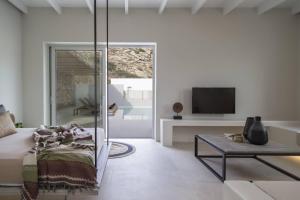 a living room with a couch and a tv at Hide Out Suites in Mylopotas