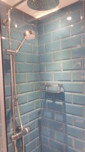 y baño con ducha y pared de azulejos azules. en Beaumond Cross Inn, en Newark-on-Trent
