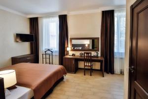 una camera d'albergo con letto, scrivania e specchio di Guest house Kolibri a Gelendzhik