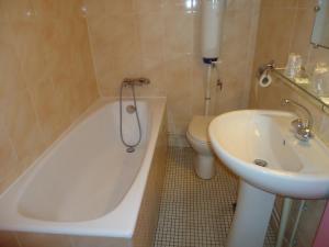 a bathroom with a toilet and a tub and a sink at Hotel des Belges in Paris