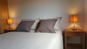 a bedroom with a white bed with two lamps on tables at Quinta Do Acipreste (Antiga Quinta Da Torre) in Lamego