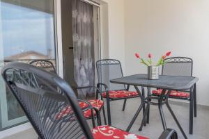 een zwarte tafel en stoelen met bloemen op een balkon bij Apartments Michelle in Crikvenica