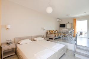 a white room with a bed and a dining room at Phaedra Hotel in Stalos