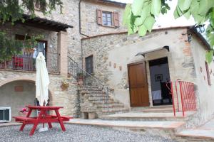 una mesa roja y una sombrilla frente a un edificio en Camere Alabastro Fontesettimena en Volterra