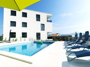 a hotel swimming pool with chairs and an umbrella at Petra's Place - Sea view apartment in Slatine