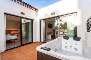 a bathroom with a tub and a bedroom at Vanilla Garden Boutique Hotel - Adults Only in Playa de las Americas