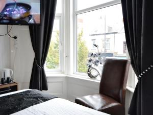a bedroom with a bed and a chair and a window at South Shore Guest House in South Shields