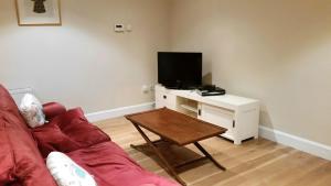 a living room with a couch and a table with a tv at Apartment 2 Oakleigh House in Cork