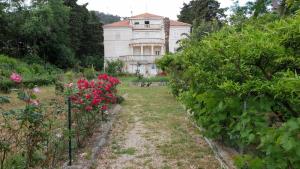 an old house in the middle of a garden with roses at Apartment Lju on the Beach in Split