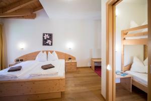 a bedroom with two beds and a bunk bed at Hotel Alpin in Colle Isarco