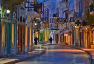a city street at night with people walking down the street at Soulas apart -Ρέα- in Ano Syros