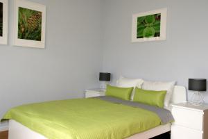 sypialnia z zielonym łóżkiem i 2 zdjęciami na ścianie w obiekcie Apartament PP6/15 w Warszawie