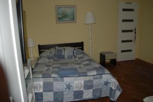 a bedroom with a bed with a blue and gray quilt at Homestay Kapitańska 9 in Gdynia