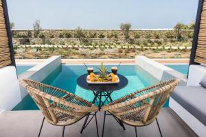 eine Terrasse mit einem Tisch, 2 Stühlen und einem Pool in der Unterkunft My Mykonos Hotel in Mykonos Stadt
