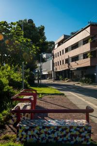 a row of benches sitting on the side of a street at Hotel Metropolitano in Coronel Fabriciano