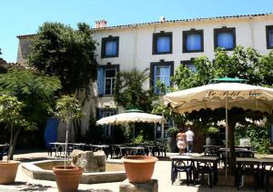 un edificio con tavoli e ombrelloni in un cortile di Mobilhome Climatisé 3CH 6P dans Parc des 7 Fonts ad Agde