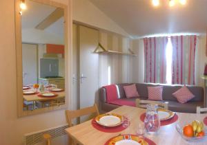 sala de estar con mesa y sofá en Mobilhome Climatisé 3CH 6P dans Parc des 7 Fonts en Agde