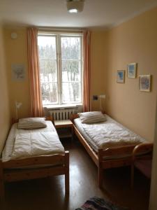 two beds in a room with a window at Tvetagårdens Vandrarhem in Södertälje