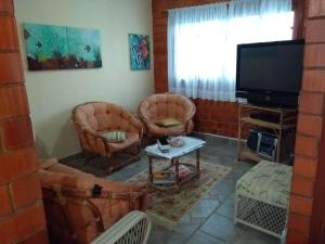 a living room with chairs and a flat screen tv at Casa praia Camburi com piscina in Camburi