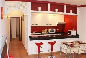 una cocina con armarios rojos y blancos y una mesa en Apartamentos JANESKA, en Tías