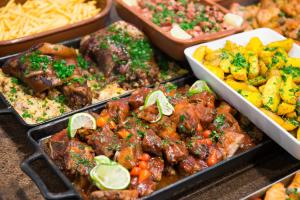 a buffet of food with meat and vegetables in trays at Hotel Metropolitano in Coronel Fabriciano