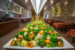 a large tray of food with vegetables on a table at Hotel Metropolitano in Coronel Fabriciano