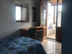 Schlafzimmer mit einem Bett, einem Schreibtisch und einem Waschbecken in der Unterkunft Pensione La Nassa in Stromboli