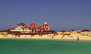 a group of people on a beach with a building at El Cotillo Casa Checa 4 in El Cotillo