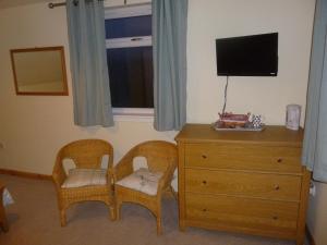ein Schlafzimmer mit 2 Stühlen, einer Kommode und einem TV in der Unterkunft Goldenhill in Portree