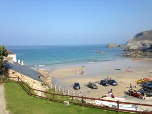 Una playa con un grupo de personas y coches en ella. en Rosenn Teyr, en St. Agnes
