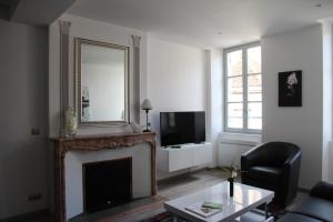 een woonkamer met een open haard en een spiegel bij Le Beau Carnot in Beaune