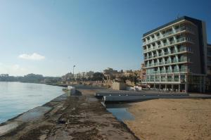 a building on the beach next to the water at Water's Edge Hotel in Birżebbuġa