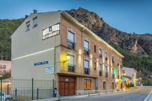 a building on a street in front of a mountain at Hotel Parras Arnedillo in Arnedillo